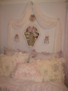 a white bed topped with lots of pillows and a pink canopy over it's headboard