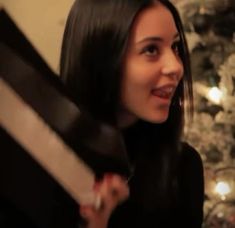 a woman holding a present in front of a christmas tree