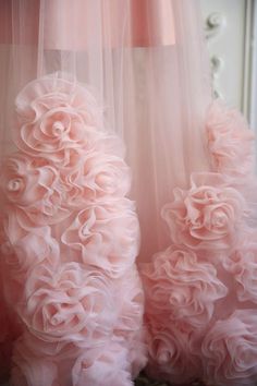 two pink dresses with flowers on them are hanging in front of a mirror and the dress is made out of tulle