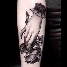 a black and white photo of a hand holding a knife with flowers on it's arm