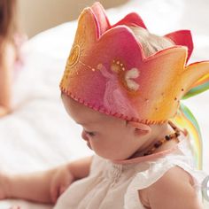 a baby wearing a colorful crown on top of a bed