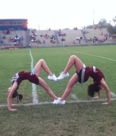 two cheerleaders doing handstand on the sidelines