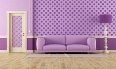 a purple couch sitting in front of a wall with polka dots on it and a lamp next to it