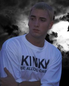 a man with his arms crossed standing in front of dark clouds