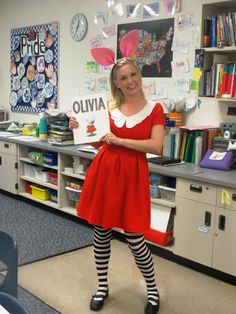 a woman in a red dress and striped socks standing in front of a desk with books on it