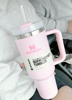 a person holding a pink coffee cup in their hand while sitting on a car seat