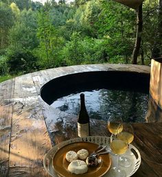 two glasses of wine and some food on a table in front of a hot tub