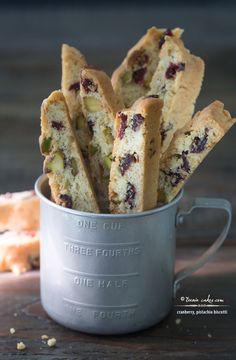 a metal cup filled with cookies on top of a wooden table