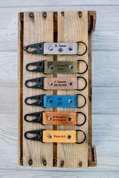 four pairs of scissors are hanging on a wooden rack with leather tags attached to them