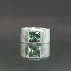 Specifications: Metal: Sterling Silver Stone: Natural Green Tourmaline Square, 1.85cts Size: US 7 Entirely hand-fabricated in sterling silver, this wide band ring presents a 1.85-carat deep moss hued tourmaline in glorious Art Deco form. A subtle contrast of matte and polished finishes flank the natural gem on either side, placed in a geometric arrangement inspired by Jazz Age architectural details. Sized to a 7, this ring is one of kind by nature of its stone and available to ship within 3 busi Wide Band Ring, Jazz Age, Wide Band Rings, Architectural Details, Green Tourmaline, Wide Bands, Sea Foam, Architecture Details, Band Ring