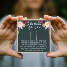 a person holding up a card with flowers on it and the words to the mother of the bride