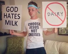 a man holding two signs that say no dairy and choose jesus not cheeses in front of him