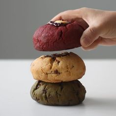 a hand is picking up a piece of food from the top of two stacked rocks