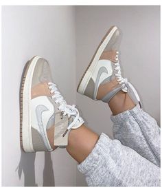 a woman's feet in white and grey sneakers with her leg up against the wall