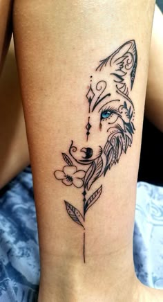 a woman's leg with a tattoo on it that has a wolf head and leaves