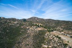 an aerial view of the mountains and road in the distance with trees on both sides