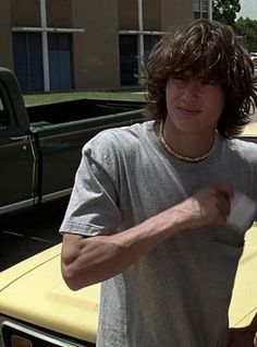 a man standing in front of a yellow car with his hand on the door handle