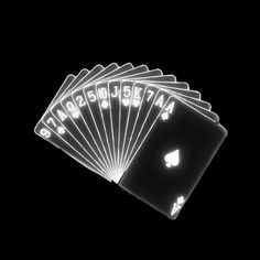 six playing cards are lit up in the dark with white letters on them, and one is