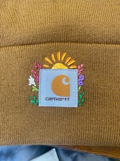 a brown beanie hat with the word campbell on it and an image of sunflowers