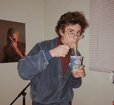 a man in glasses eating cereal from a cup