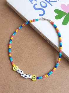 a bracelet with two smiley faces and the word happy on it next to a book