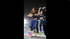 two women in blue pants and black top dancing on the ice with an american flag sticker