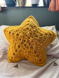 a yellow crocheted star pillow sitting on top of a bed