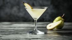 a martini glass with an apple on the side next to it and another pear in the background