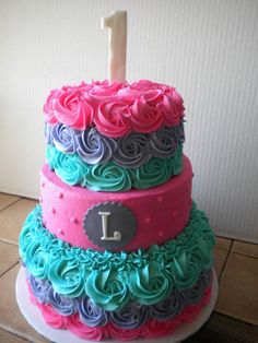 a three tiered cake with pink, blue and green frosting