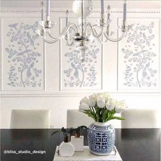 a dining room table with white flowers in a blue vase on it and wallpaper