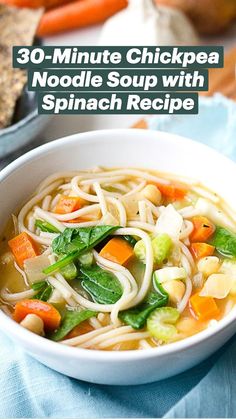 two bowls of soup with carrots, spinach and noodles on a table top