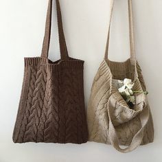 two purses are hanging on the wall next to each other and one has a flower in it