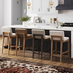 a kitchen island with four stools in front of it and an area rug on the floor