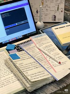 an open laptop computer sitting on top of a desk next to notebooks and papers