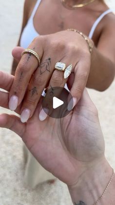 a woman holding her hand out with two rings on it