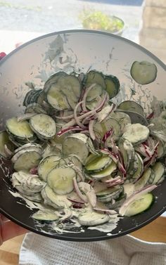 a bowl filled with cucumbers and onions on top of a table