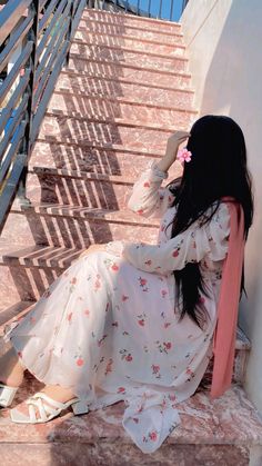 a woman is sitting on the stairs with her hand in her hair