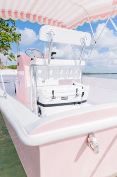 a pink and white boat in the water with a canopy over it's head