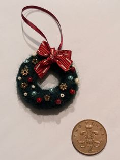 a small christmas wreath ornament next to a penny