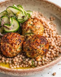 a bowl filled with meatballs, beans and cucumber slices on top of it