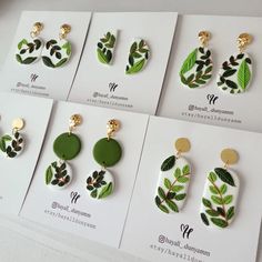 four pairs of earrings with green leaves and gold accents on white carded envelopes