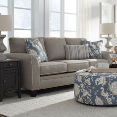 a living room scene with focus on the couch and chair, coffee table and ottoman