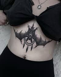 a woman's stomach with a bat tattoo on her belly and an evil symbol