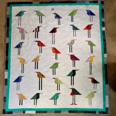 a quilted wall hanging with colorful birds on it's sides and in the middle