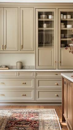 a kitchen with beige cabinets and white counter tops, an area rug on the floor