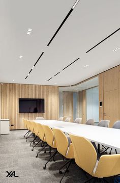 an empty conference room with yellow chairs and a flat screen tv mounted on the wall