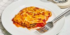 a white plate topped with lasagna next to a fork