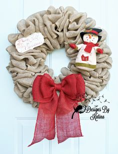 a burlock wreath with a snowman on it and a red bow hanging from the front door