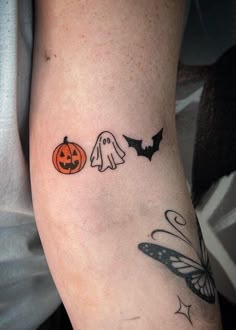 a person with a tattoo on their arm has a butterfly, ghost and halloween pumpkin