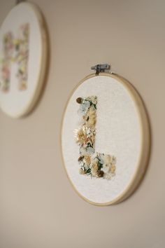 there are two embroiderys hanging on the wall next to each other, one has a letter j